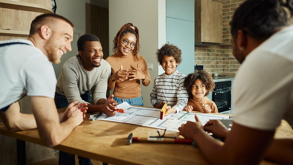 Happy African American family communicating with manual workers in moving house.