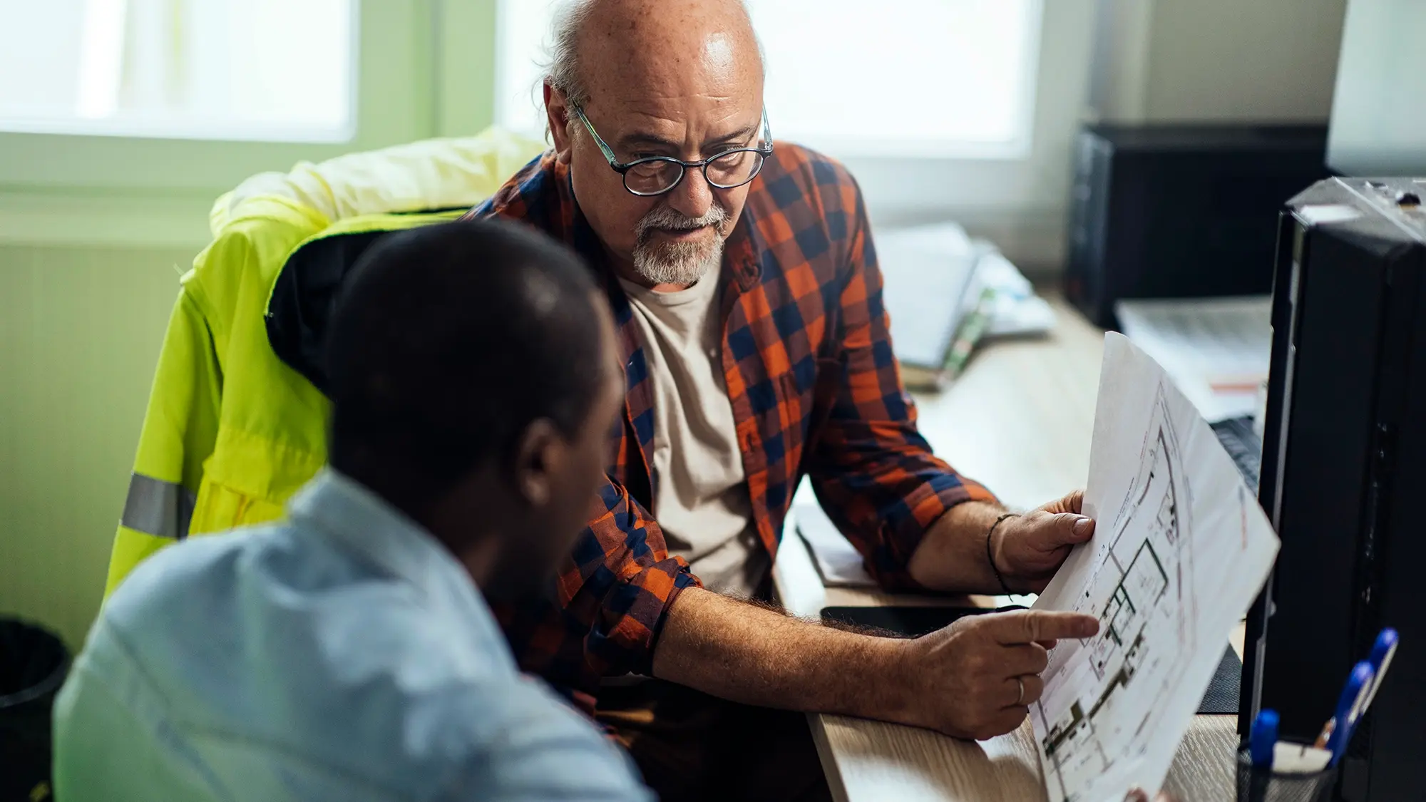 Two colleagues looking over architectural plans while working at a construction site