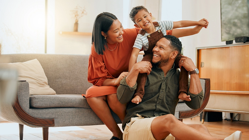 A happy mixed race family of three relaxing in the lounge and being playful together. Loving black family bonding with their son while playing fun games on the sofa at home